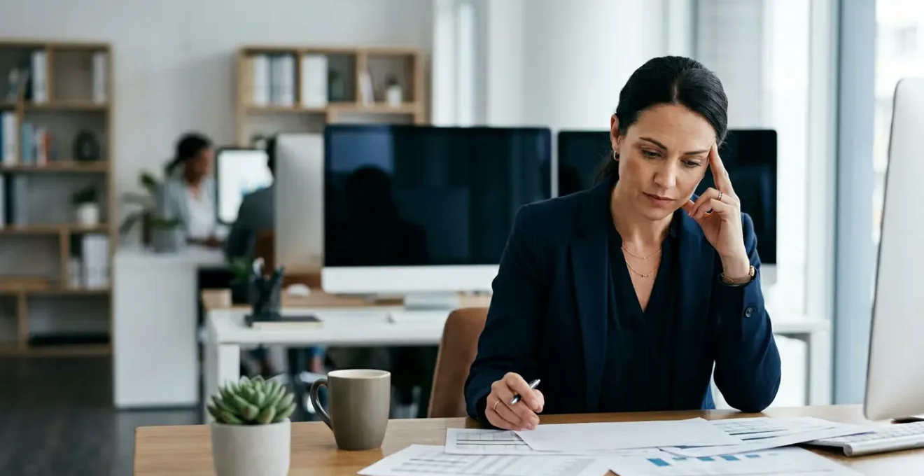 Professional accountant in modern office environment during year-end closing period showing focused determination amid complex financial documents